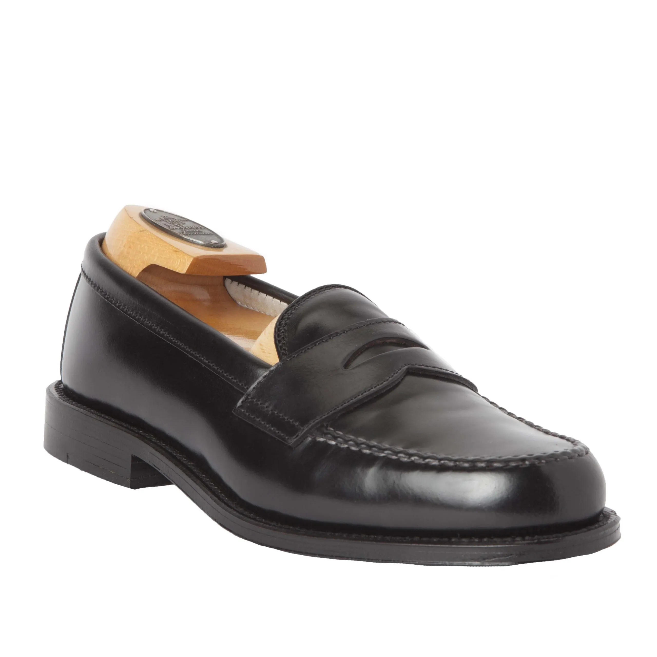 The Alden Madison 987 - Leisure Hand Sewn loafer is crafted in black Shell Cordovan, featuring a classic penny design, visible stitching, and a low heel. It includes a wooden shoe tree and has a durable Leather Outsole with a subtle right angle for added e
