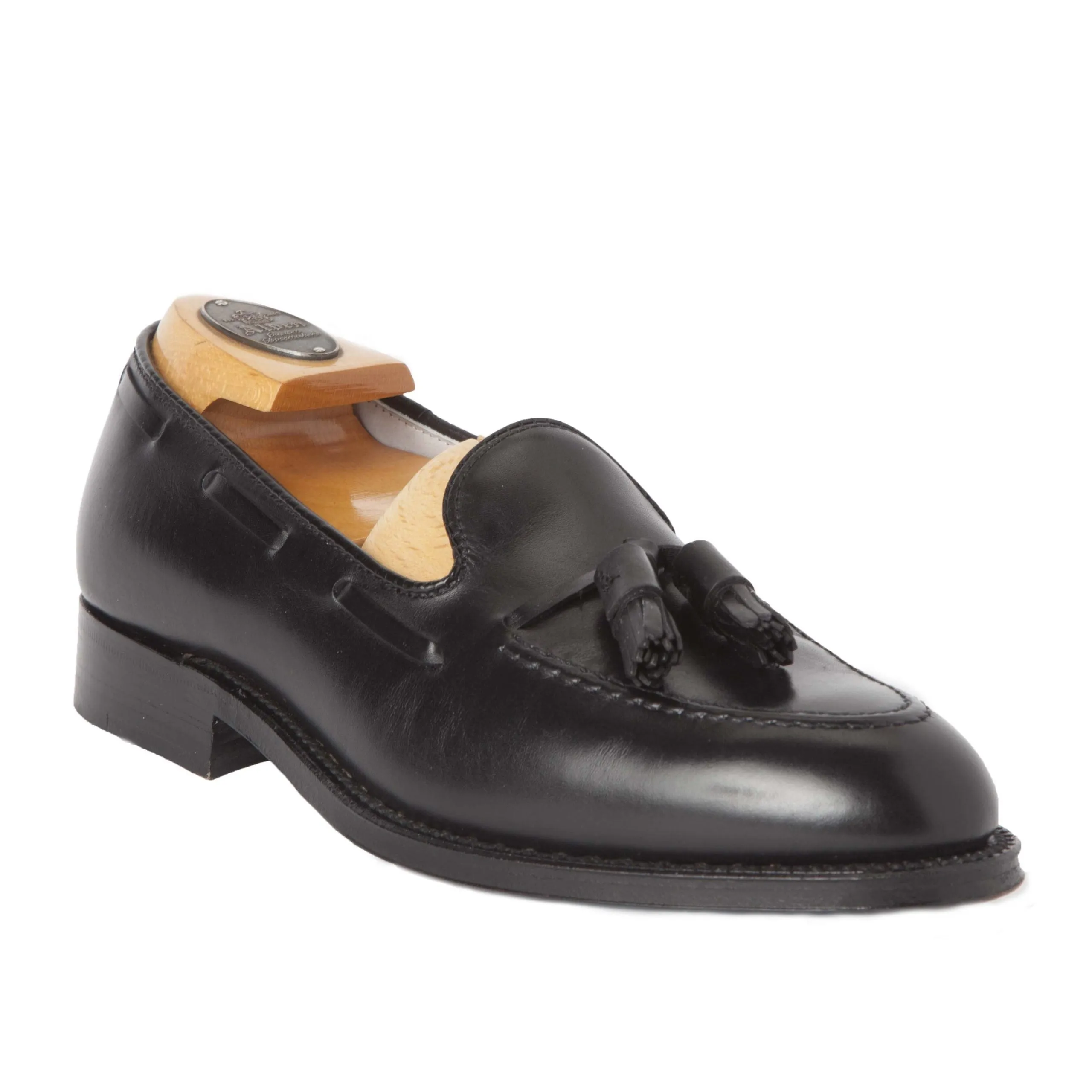 The Alden Madison 660 - Tassel Loafer in Black Calfskin rests against a plain background. Crafted on the sleek Aberdeen Last, it has a polished finish and comes with a beige shoe tree to maintain its shape.