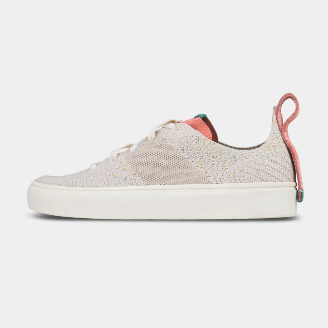 A pair of women's sneakers with a knit upper in a beige color, featuring premium leather accents and a lace-up closure system.A pair of off-white knitted sneakers with light pink speckles. The shoes have white laces, a pale pink tongue, and a pink and whi